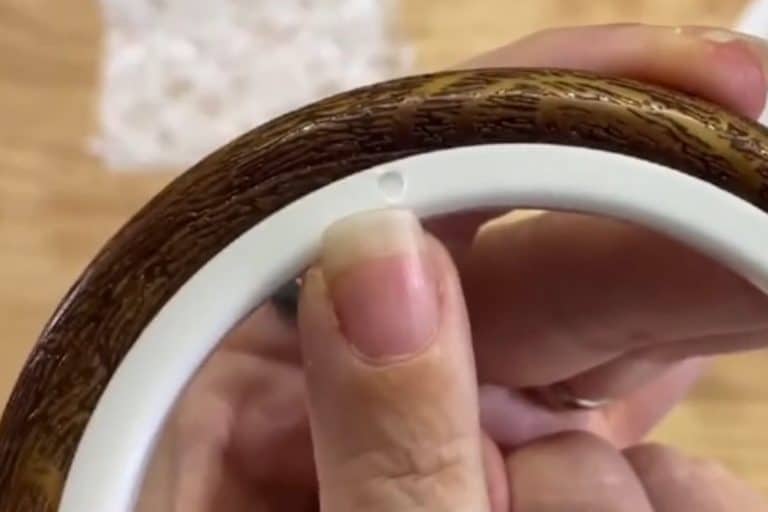 Finger points to the inner hoop of a faux wood vinyl embroidery hoop showing the mold pour circle