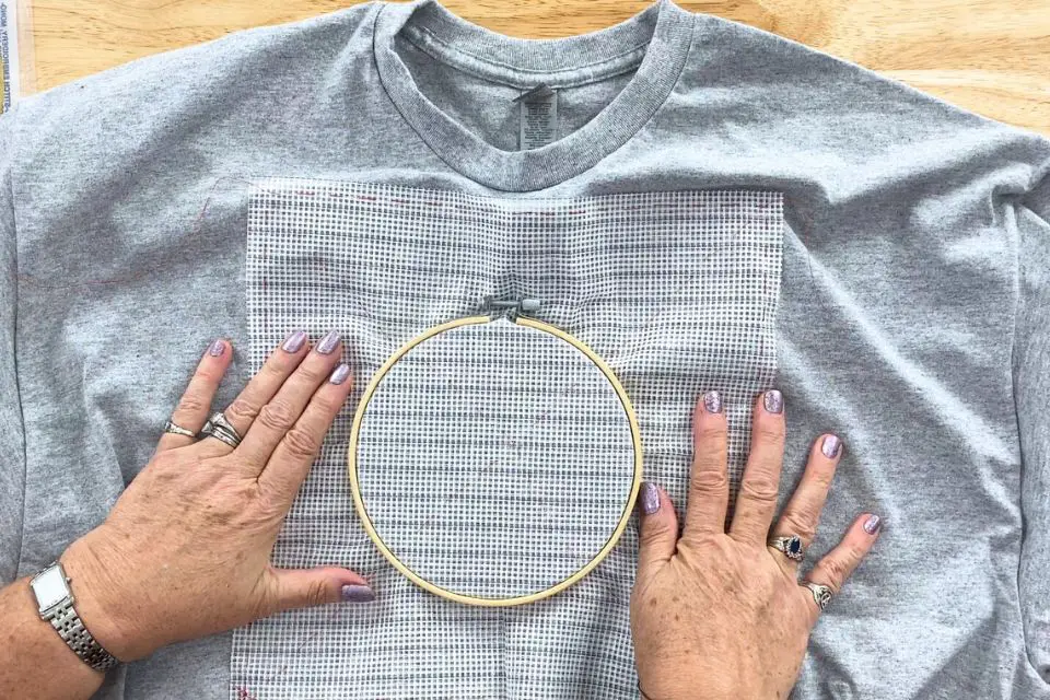 Embroidery hoop placed on a t-shirt with waste canvas