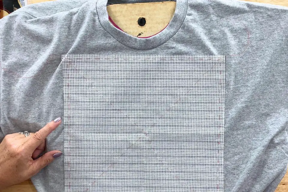 Waste canvas is basted on a t-shirt along the edge and in both diagonal directions