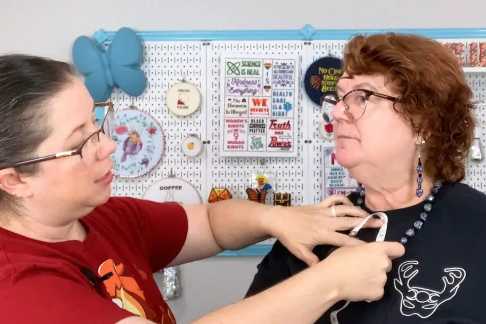 Sarah is measuring the neckline of Bridget's t-shirt.