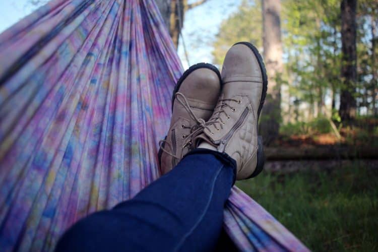 Two feet in shoes swinging in a purple hammock